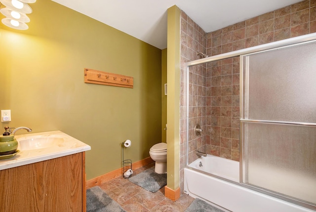 bathroom featuring tile patterned flooring, baseboards, toilet, combined bath / shower with glass door, and vanity