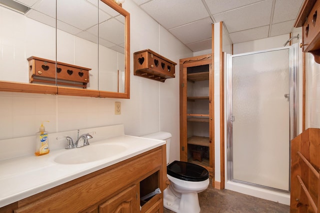 bathroom with a drop ceiling, a stall shower, toilet, and vanity