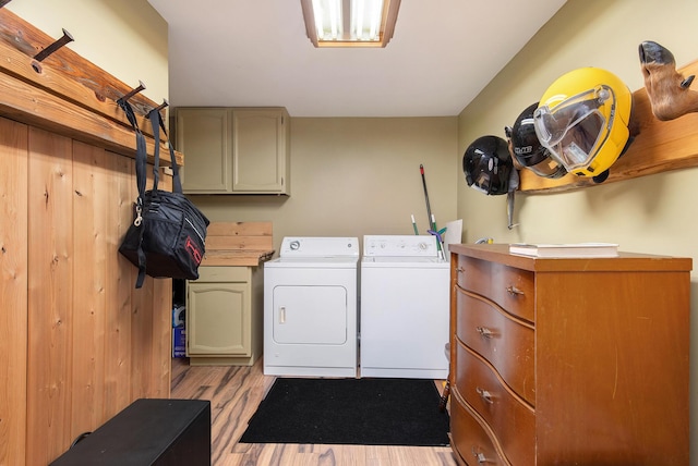 washroom with separate washer and dryer, light wood-style flooring, and cabinet space