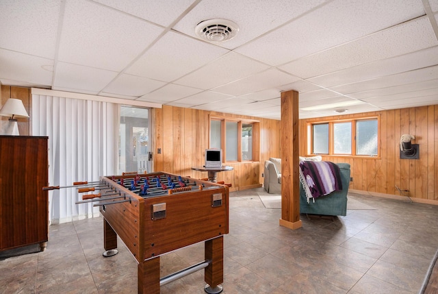 game room featuring a drop ceiling, visible vents, baseboards, and wood walls