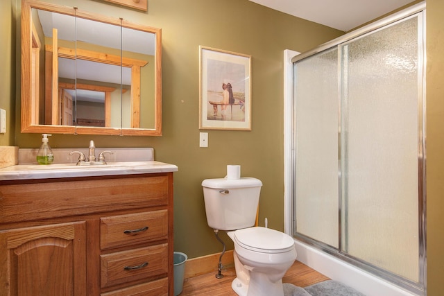 bathroom featuring vanity, wood finished floors, baseboards, a stall shower, and toilet