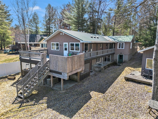 rear view of property featuring a wooden deck, stairs, a standing seam roof, and metal roof