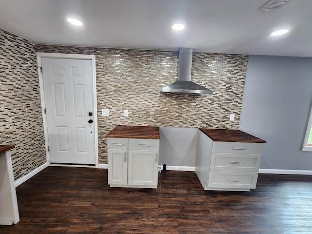 kitchen featuring dark wood finished floors, butcher block countertops, recessed lighting, and wall chimney range hood