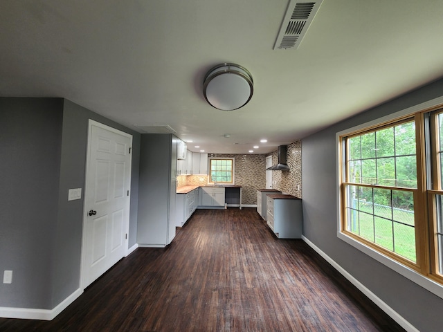 kitchen featuring visible vents, recessed lighting, wall chimney range hood, baseboards, and dark wood-style flooring
