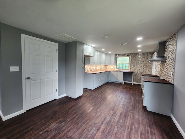 kitchen featuring tasteful backsplash, baseboards, recessed lighting, wall chimney exhaust hood, and dark wood-style flooring