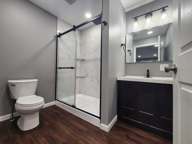 bathroom featuring vanity, wood finished floors, baseboards, a marble finish shower, and toilet
