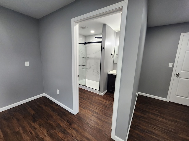 interior space featuring a marble finish shower, baseboards, and wood finished floors