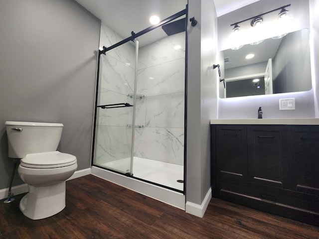 full bathroom with toilet, wood finished floors, a marble finish shower, baseboards, and vanity