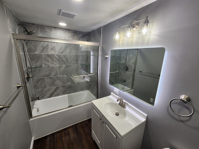 bathroom featuring vanity, wood finished floors, visible vents, and enclosed tub / shower combo