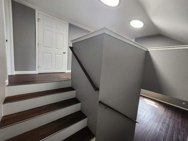 stairway featuring vaulted ceiling, baseboards, and wood finished floors
