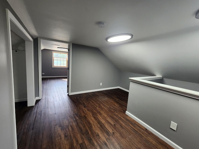 additional living space with baseboards, lofted ceiling, and dark wood finished floors
