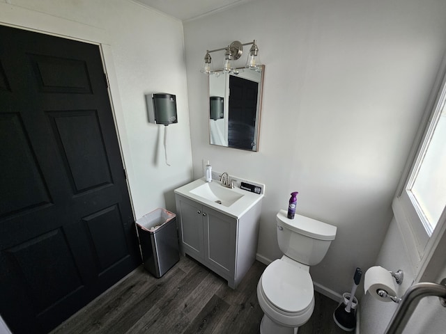 half bath with toilet, vanity, baseboards, and wood finished floors