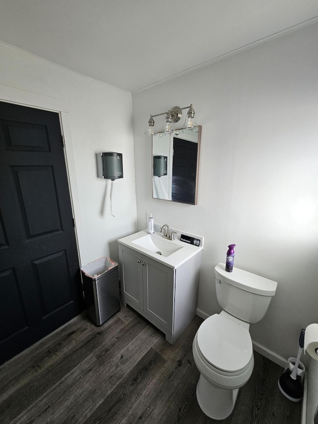 half bath featuring baseboards, toilet, wood finished floors, and vanity