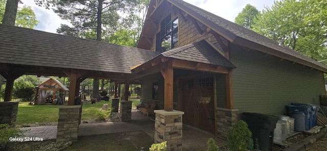 exterior space with a patio area, a shingled roof, and a yard