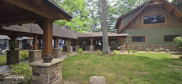 back of property featuring a patio, a yard, and roof with shingles