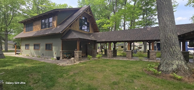 view of front of home with a front yard, stone siding, and a shingled roof