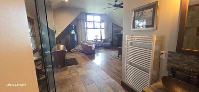 entrance foyer featuring lofted ceiling, radiator heating unit, a fireplace, and ceiling fan