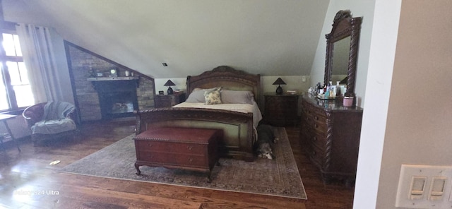 bedroom with a fireplace, lofted ceiling, and wood finished floors