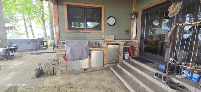 view of patio featuring exterior kitchen, area for grilling, and a hot tub