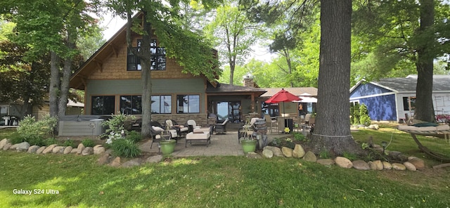 rear view of house with a patio area, stone siding, a lawn, and a hot tub