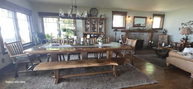 dining area with a stone fireplace, an inviting chandelier, and wood finished floors