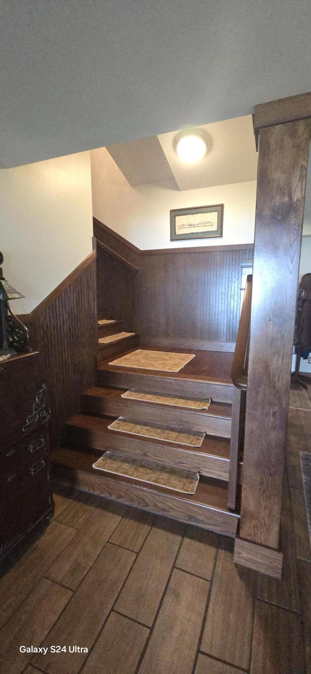 staircase featuring wood tiled floor and wainscoting