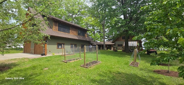 view of yard featuring a vegetable garden, a garage, and driveway