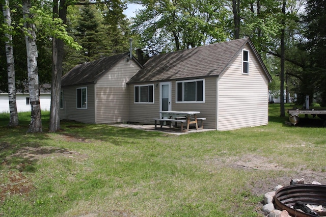 rear view of house with a patio area, a lawn, and a shingled roof