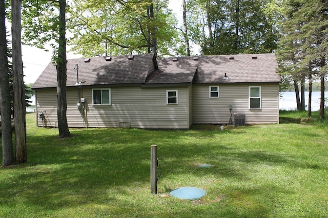 rear view of house featuring a lawn, a shingled roof, and central AC