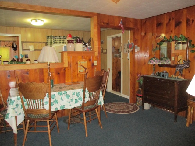 dining area featuring carpet and wood walls