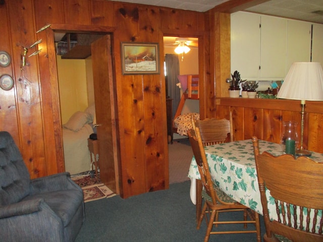 dining room featuring wood walls and carpet