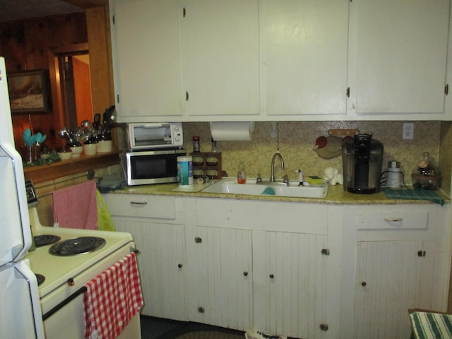 kitchen featuring tasteful backsplash, stainless steel microwave, light countertops, white cabinetry, and a sink