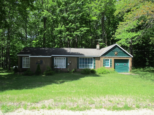 ranch-style house featuring a front lawn, an attached garage, and a chimney