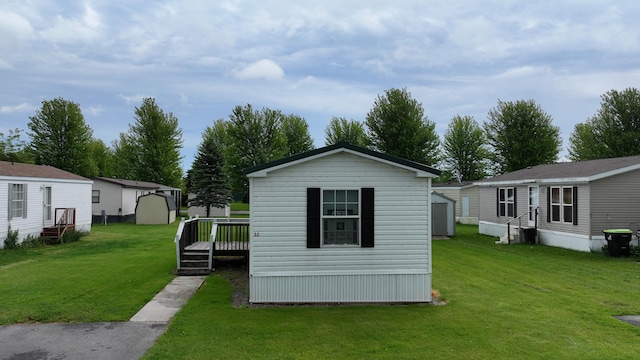 exterior space featuring a storage unit, an outbuilding, a lawn, and entry steps