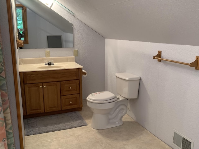 bathroom featuring visible vents, toilet, lofted ceiling, vanity, and a textured wall