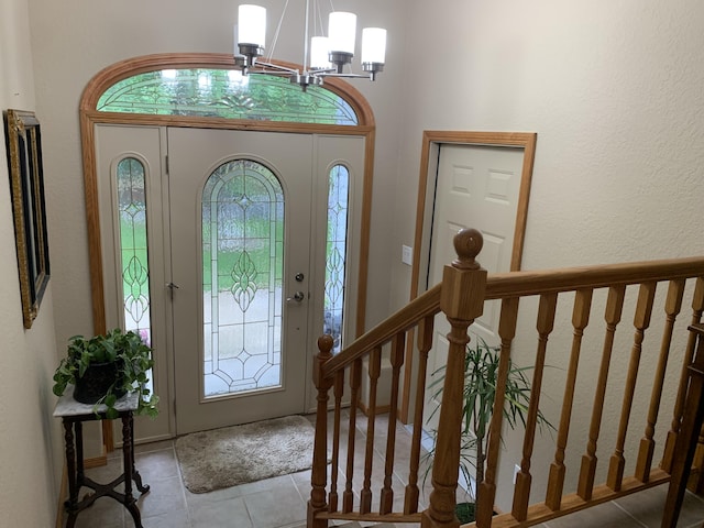 entrance foyer featuring stairs, an inviting chandelier, and tile patterned flooring