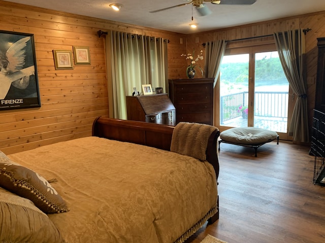 bedroom with a ceiling fan, access to exterior, wooden walls, and wood finished floors