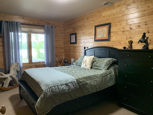 carpeted bedroom with visible vents and wood walls