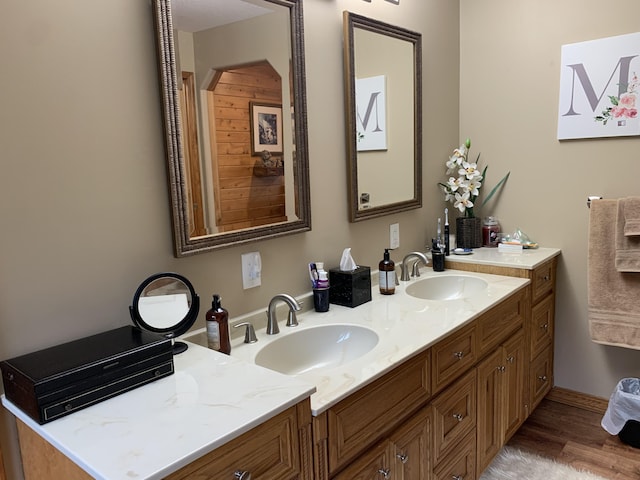 full bathroom featuring double vanity, wood finished floors, and a sink