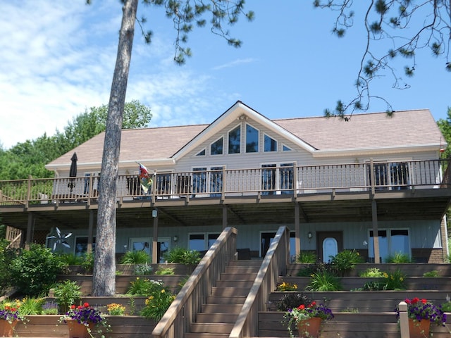 back of house featuring stairway, a vegetable garden, a deck, and a shingled roof