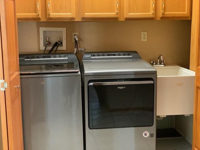 laundry room featuring separate washer and dryer, cabinet space, and a sink