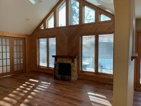 unfurnished living room featuring wood finished floors, a fireplace, french doors, and high vaulted ceiling