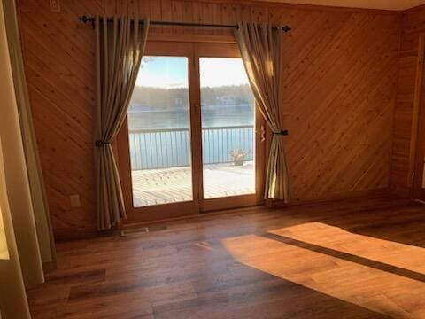 unfurnished room with wooden walls, wood finished floors, and a water view