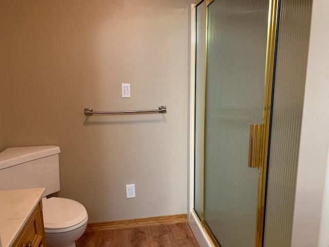 full bath featuring toilet, wood finished floors, a shower stall, baseboards, and vanity