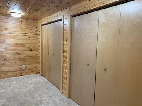 interior space featuring wooden ceiling, wooden walls, and carpet flooring