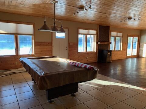 recreation room with a wealth of natural light, wood ceiling, wood walls, and tile patterned floors