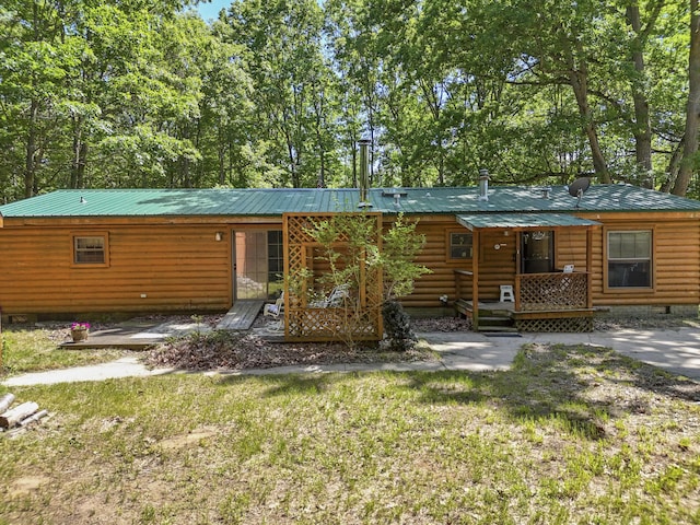 view of front facade with log veneer siding, crawl space, metal roof, and a front lawn