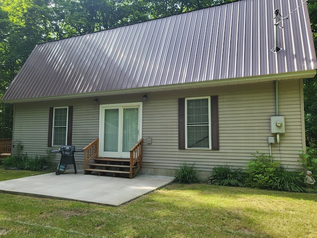 back of property with a patio area, a lawn, entry steps, and metal roof