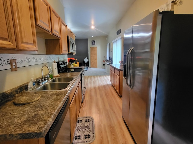 kitchen featuring dark countertops, brown cabinets, stainless steel appliances, and a sink