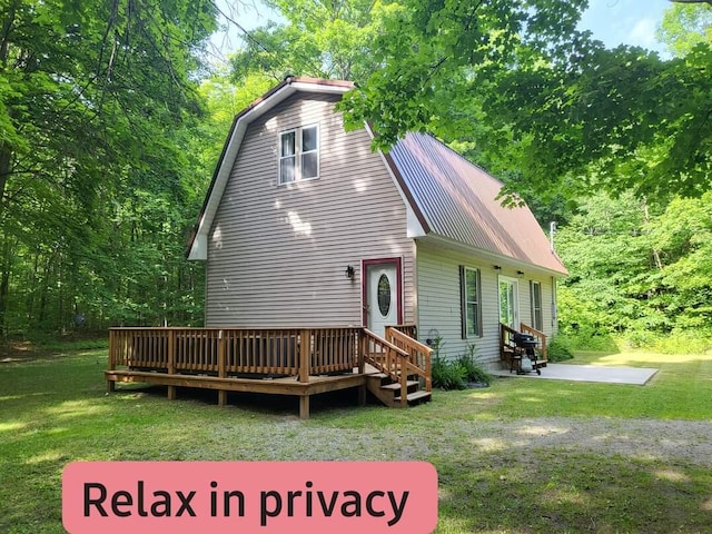 back of house with a gambrel roof, entry steps, a yard, a wooden deck, and metal roof